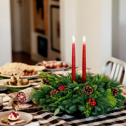 Centerpiece made of noble fir, pine, incense cedar and bay leaves with egg-sized ponderosa pine cones, red berry clusters, and 2 red 12" taper candles