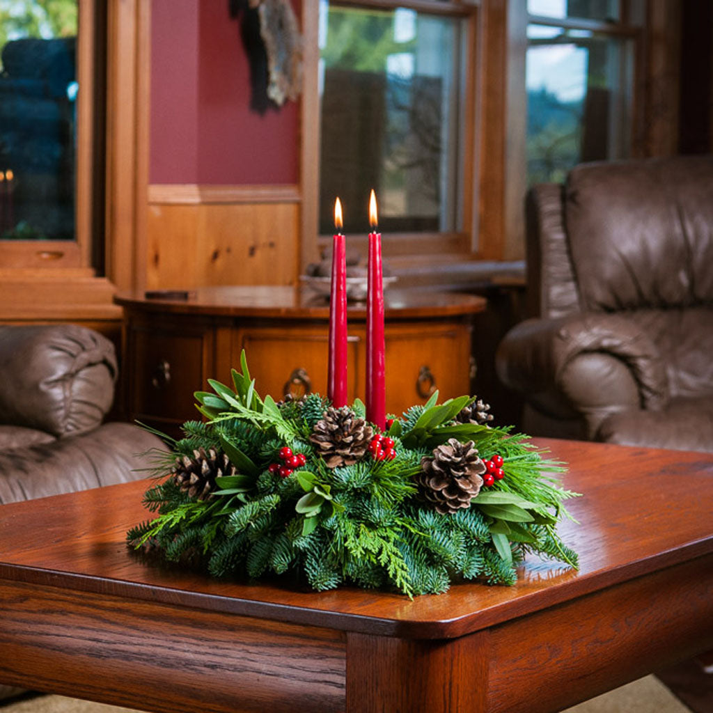 Centerpiece made of noble fir, pine, incense cedar and bay leaves with egg-sized ponderosa pine cones, red berry clusters, and 2 red 12" taper candles