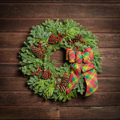 red decorations with red and green plaid bow on evergreen wreath