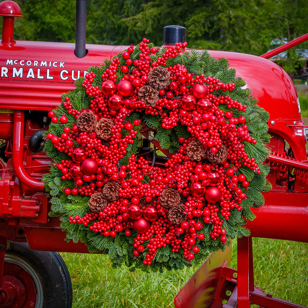 Christmas wreath made of noble fir and white pine with a ring of faux red pepperberries, red ball clusters, and white-pine cones