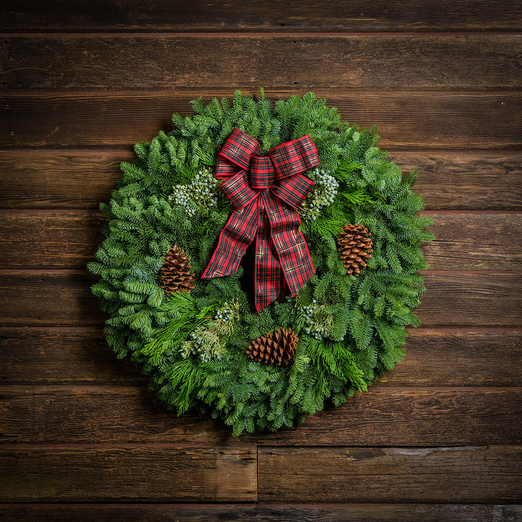 Christmas wreath of noble, cedar, juniper, pine cones and a red plaid bow