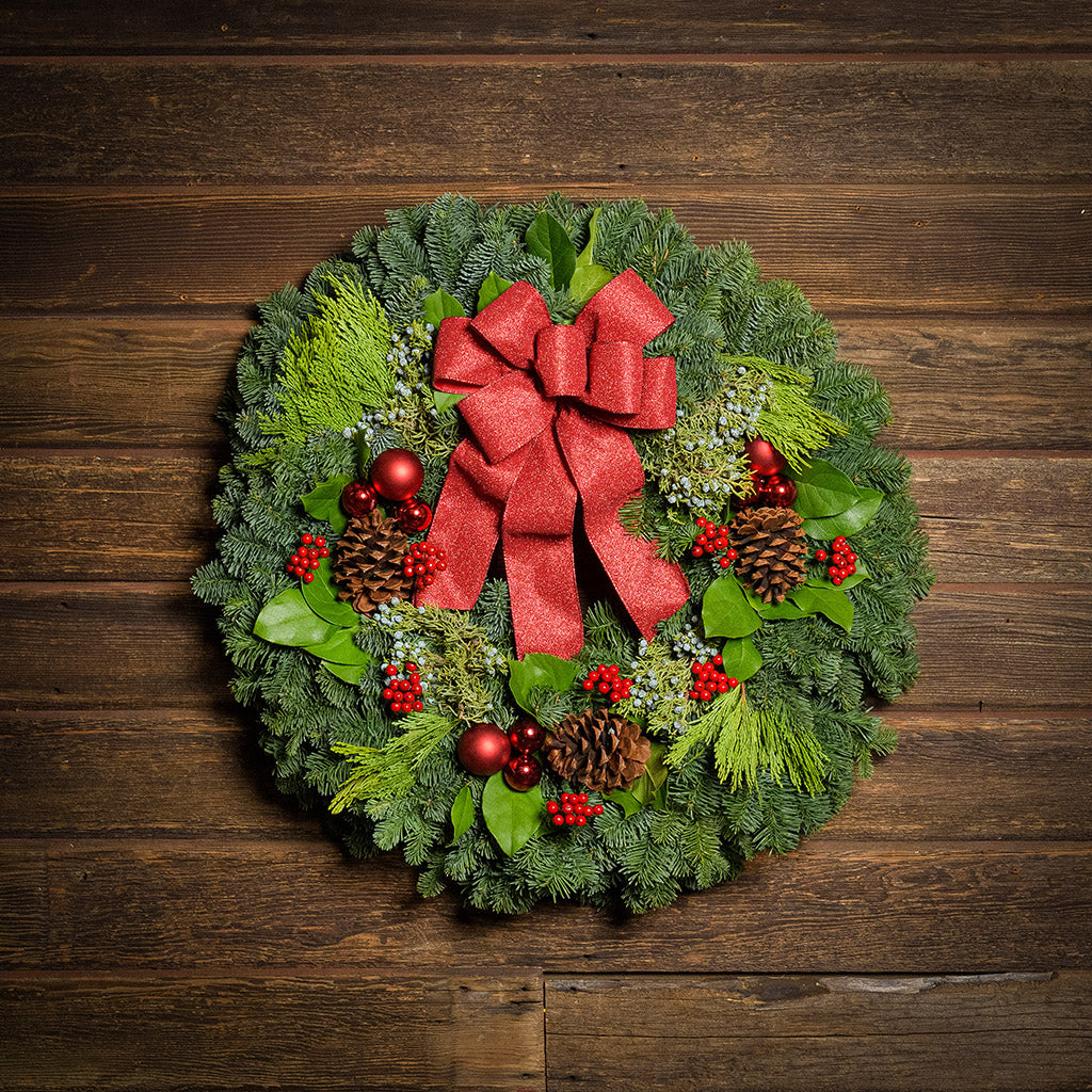 Red balls and berries with a red sparkle bow on evergreen wreath