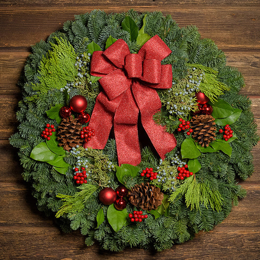 Red balls and berries with a red sparkle bow on evergreen wreath