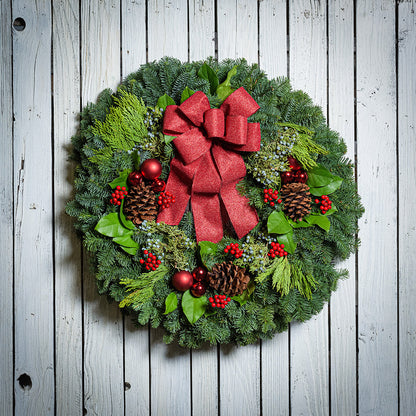 Red balls and berries with a red sparkle bow on evergreen wreath