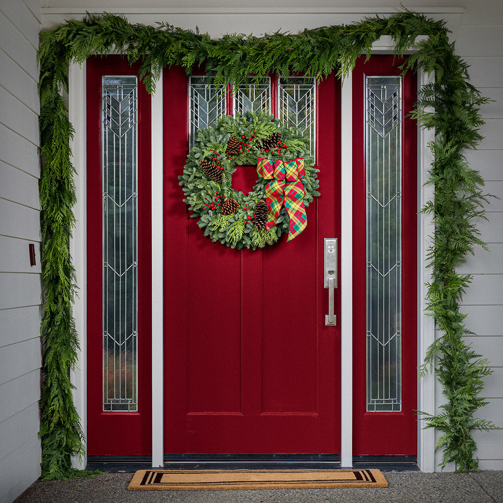 red decorations with red and green plaid bow on evergreen wreath