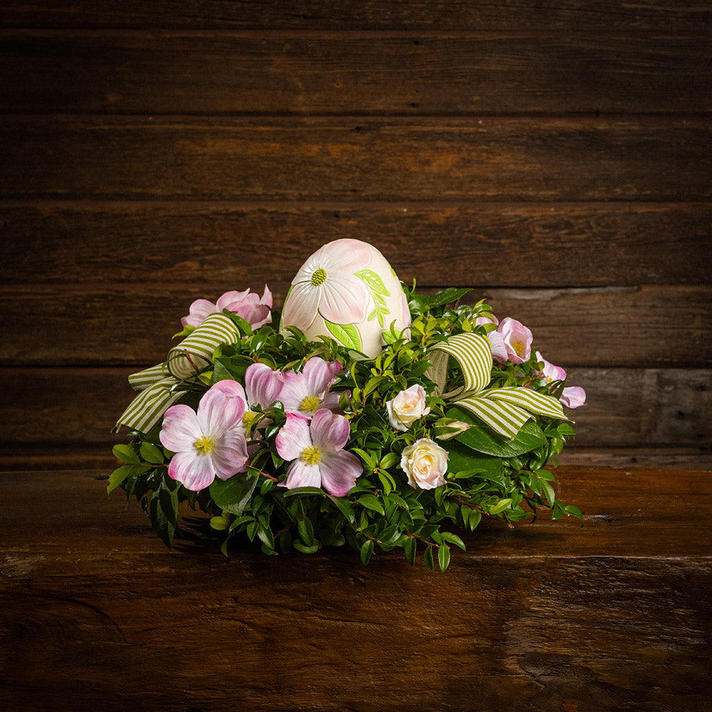 Fresh salal and green huckleberry with faux dogwood flowers, faux pink blush roses, green and ivory striped bows, and a decorative resin egg etched with dogwood flowers