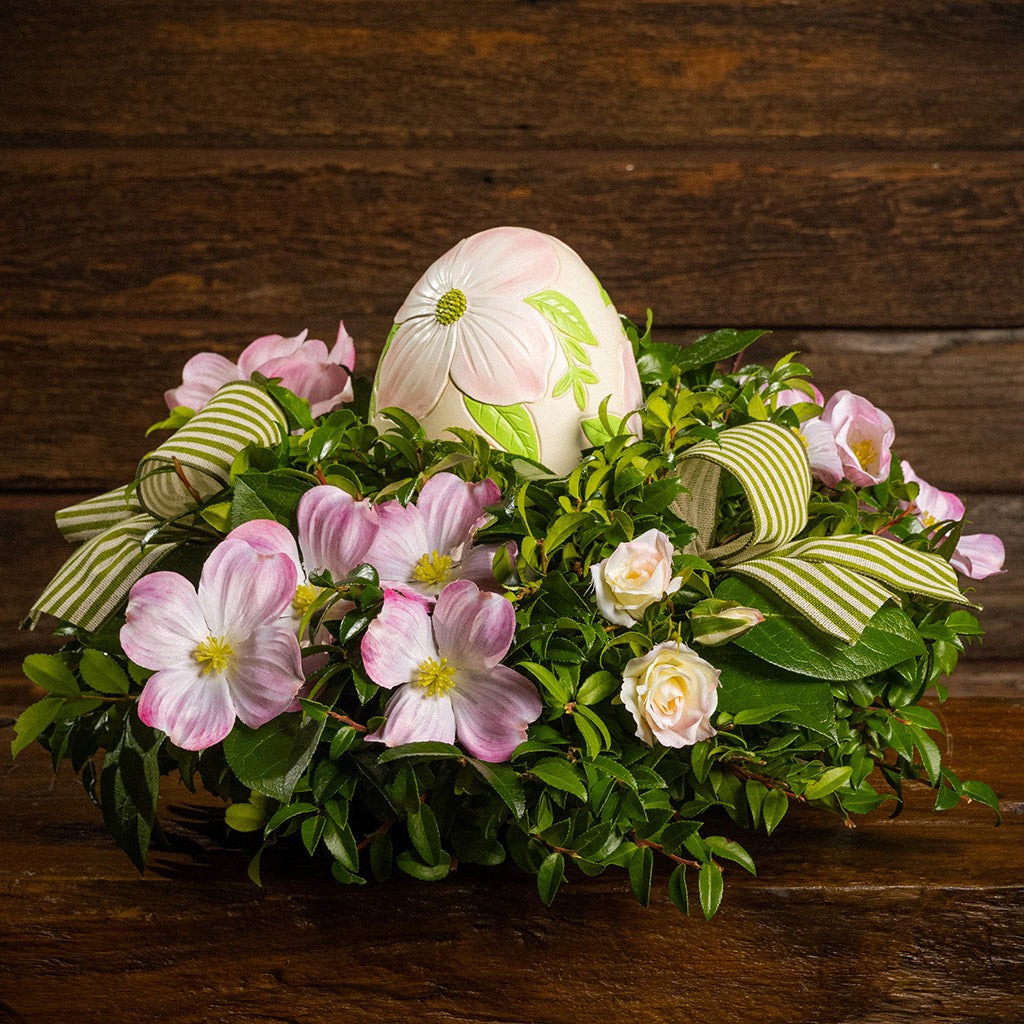 Fresh salal and green huckleberry with faux dogwood flowers, faux pink blush roses, green and ivory striped bows, and a decorative resin egg etched with dogwood flowers