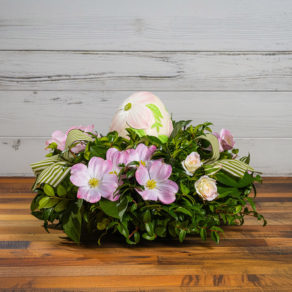 Fresh salal and green huckleberry with faux dogwood flowers, faux pink blush roses, green and ivory striped bows, and a decorative resin egg etched with dogwood flowers