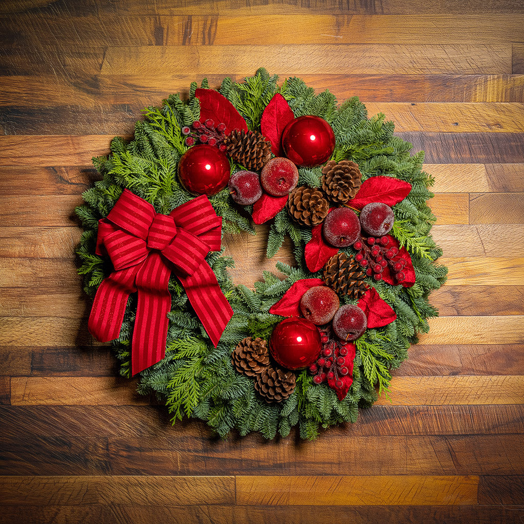 Decorative Christmas wreath with red bows, berries, and pine cones on a wooden background