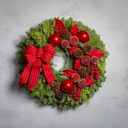 Christmas wreath with red bow, berries, and pinecones on a light gray background