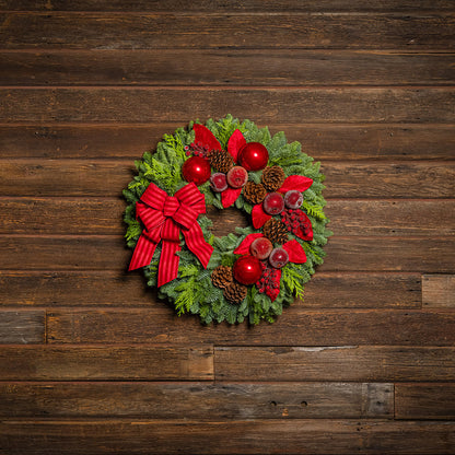 Christmas wreath with red bow and decorations on a wooden background