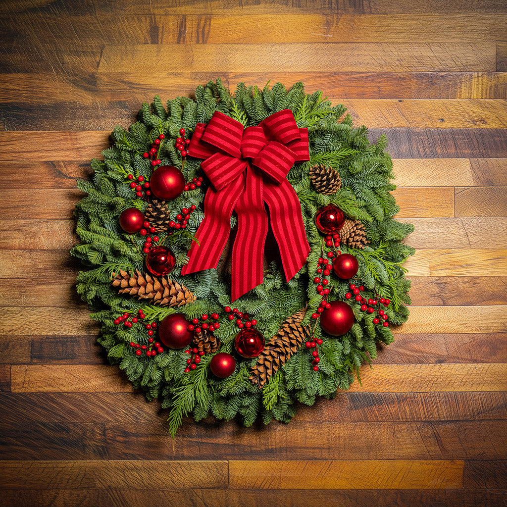 Christmas wreath with red bow and decorations on a wooden background