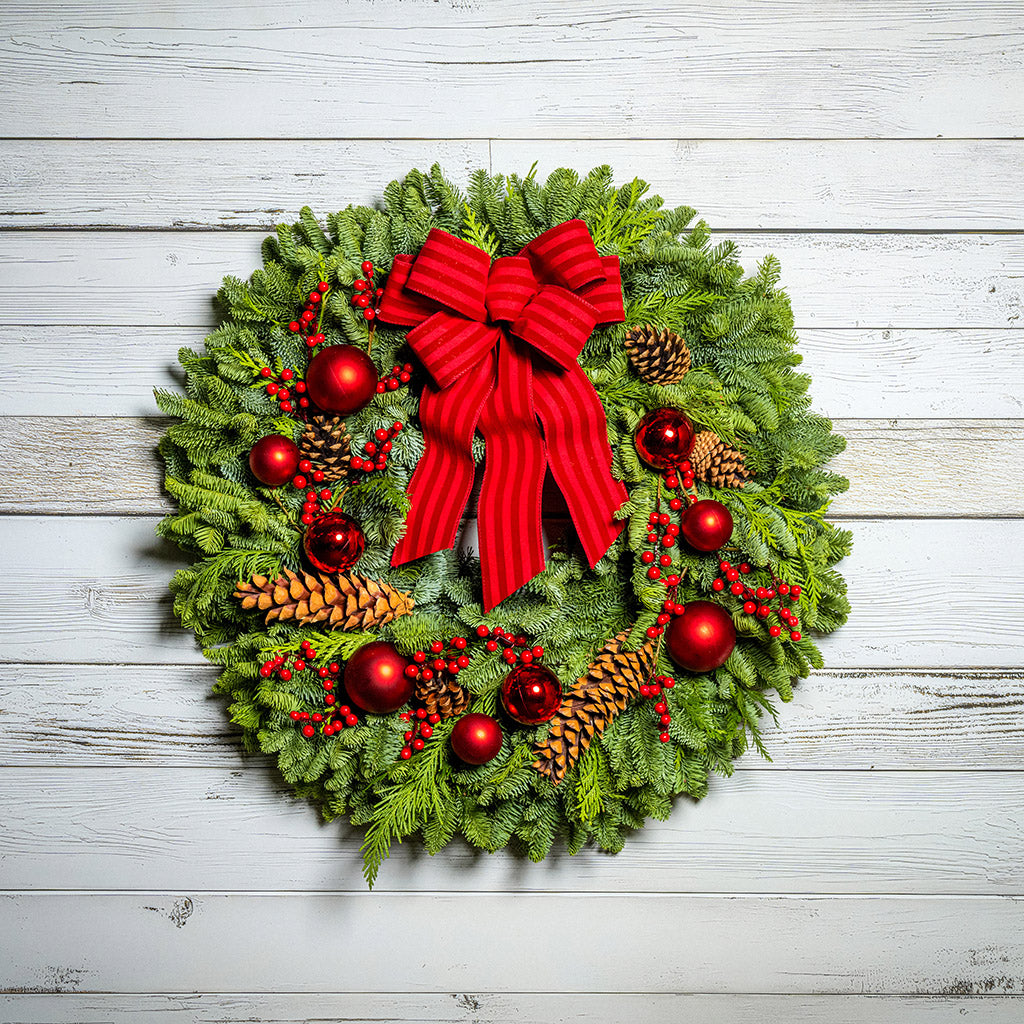 Christmas wreath with red bow and decorations on a wooden background