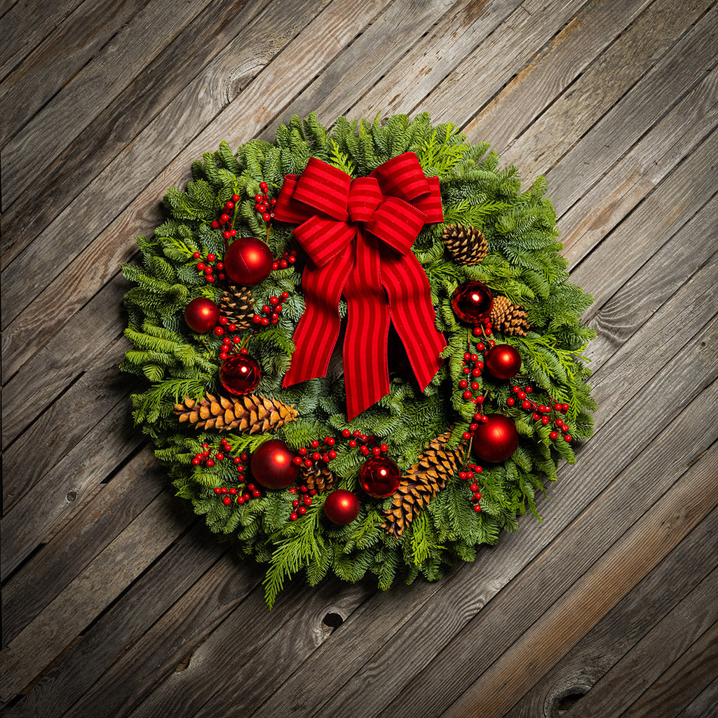 Christmas wreath with red bow and decorations on a wooden background