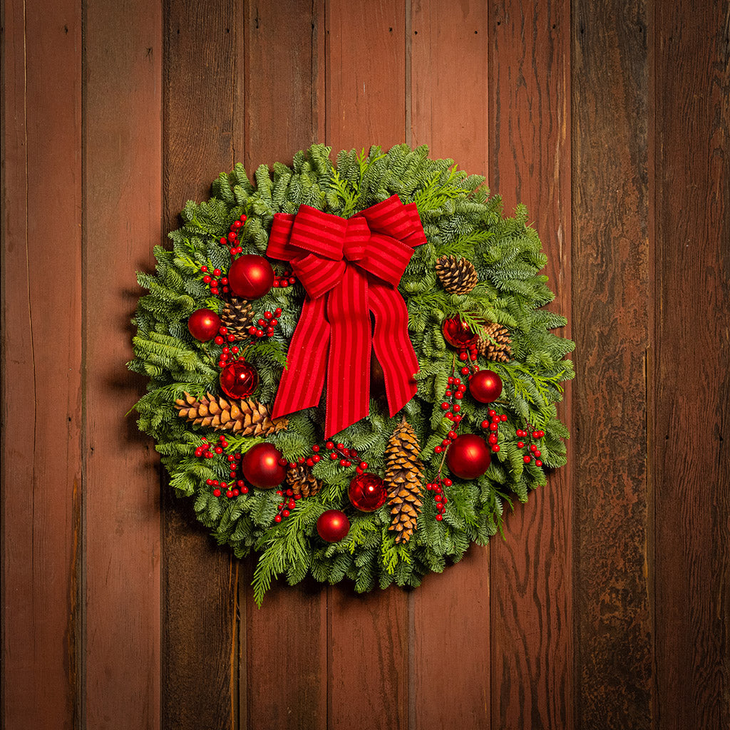 Christmas wreath with red bow and decorations on a wooden door