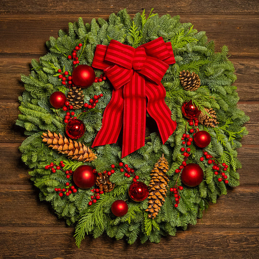 Christmas wreath with red bow, pine cones, and berries on a wooden background