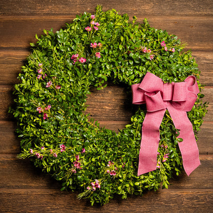 Fresh boxwood, a hand tied dusty rose bow, and faux pink wax flowers