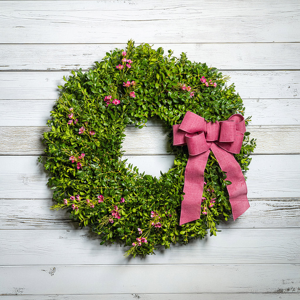 Fresh boxwood, a hand tied dusty rose bow, and faux pink wax flowers