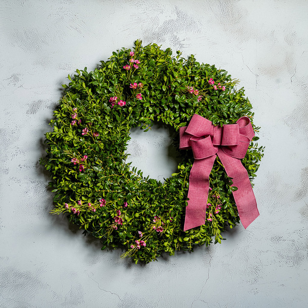 Fresh boxwood, a hand tied dusty rose bow, and faux pink wax flowers