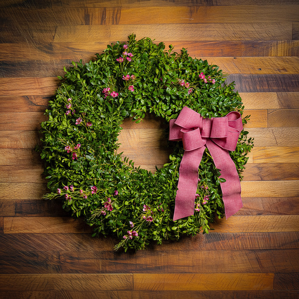 Fresh boxwood, a hand tied dusty rose bow, and faux pink wax flowers