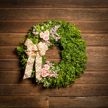 Fresh boxwood with faux lavender, peach roses, lilac, and small faux white baby’s breath flowers with a coral, cream, and green plaid bow