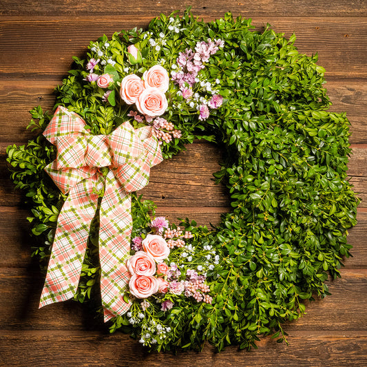 Fresh boxwood with faux lavender, peach roses, lilac, and small faux white baby’s breath flowers with a coral, cream, and green plaid bow