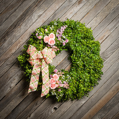 Fresh boxwood with faux lavender, peach roses, lilac, and small faux white baby’s breath flowers with a coral, cream, and green plaid bow