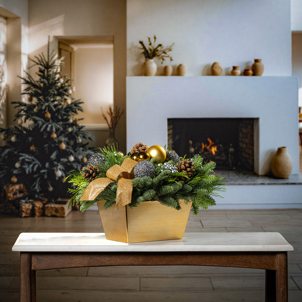 Decorative Christmas arrangement with gold bow on a table in a cozy living room.