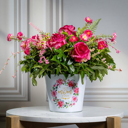 Fresh salal and green huckleberry with faux dogwood flowers and faux pink roses in a metal white floral container