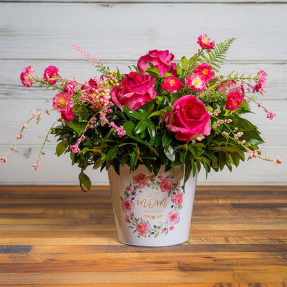 Fresh salal and green huckleberry with faux dogwood flowers and faux pink roses in a metal white floral container