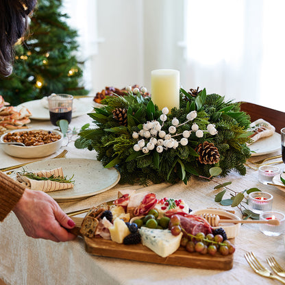 Centerpiece made of noble fir, pine, cedar and bay leaf with white berry clusters, Australian pine cones and 1 white LED pillar candle