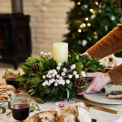 Centerpiece made of noble fir, pine, cedar and bay leaf with white berry clusters, Australian pine cones and 1 white LED pillar candle