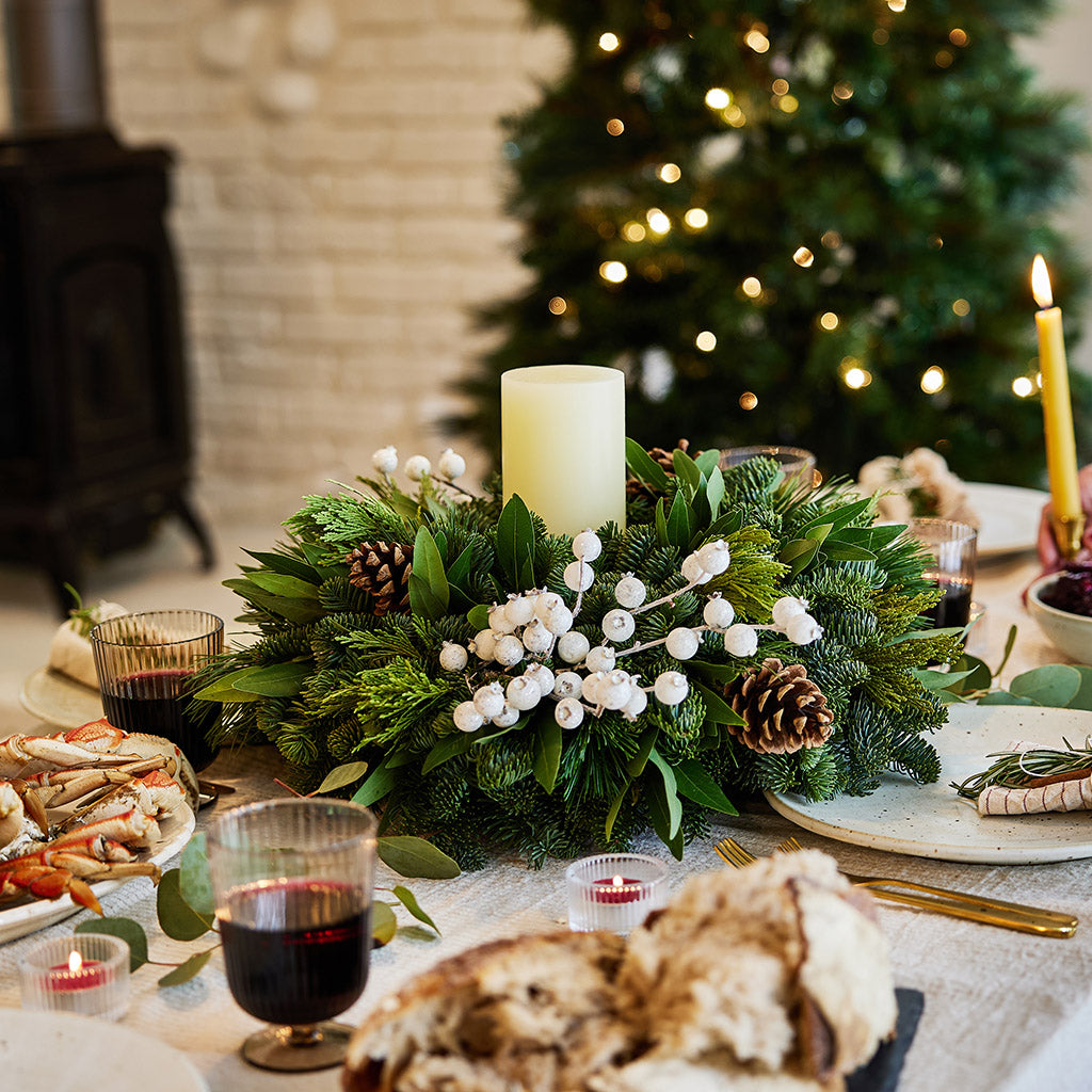 Centerpiece made of noble fir, pine, cedar and bay leaf with white berry clusters, Australian pine cones and 1 white LED pillar candle