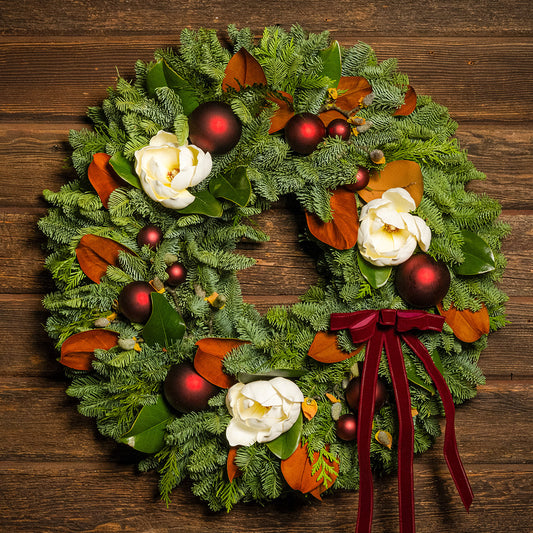 Decorative Christmas wreath with red ornaments and white flowers on a wooden background