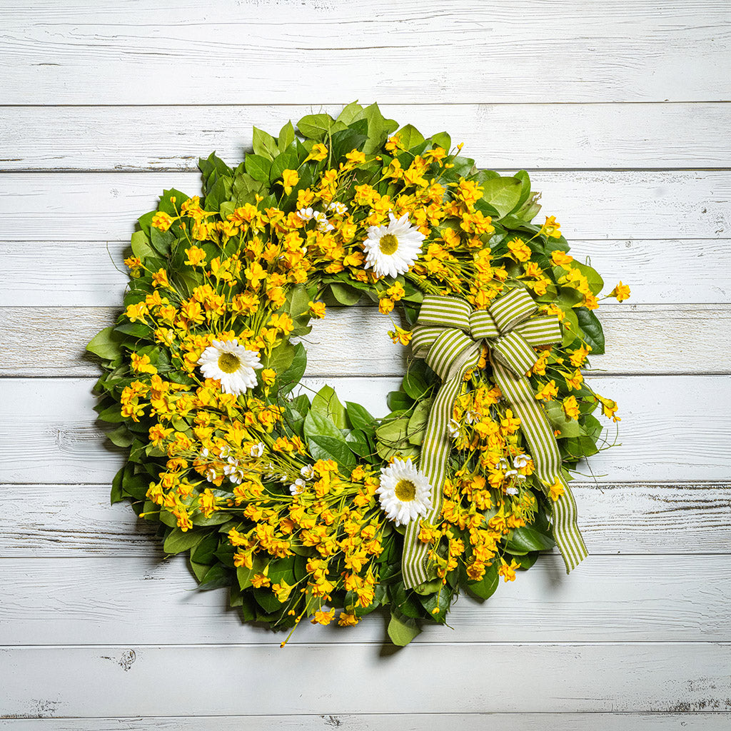 Fresh salal and sweet huckleberry with assorted faux small yellow daisies, faux white wax flowers, and faux white daisies with a sage-green and ivory striped bow