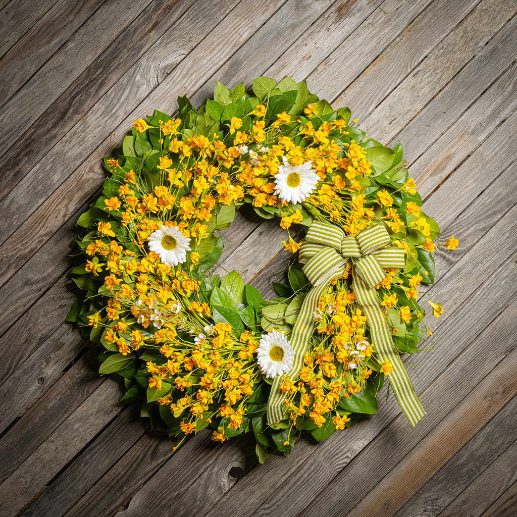 Fresh salal and sweet huckleberry with assorted faux small yellow daisies, faux white wax flowers, and faux white daisies with a sage-green and ivory striped bow