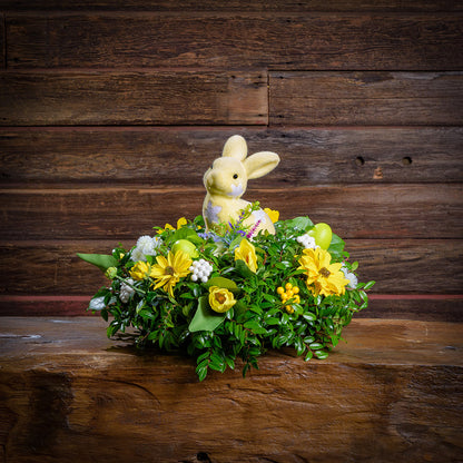 Floral arrangement with a soft bunny toy on a wooden surface and background