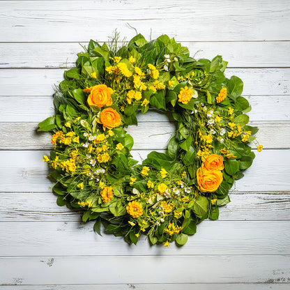 Fresh salal and sweet huckleberry with faux orange and yellow ranunculus, white wax flowers, and other mixed yellow flowers