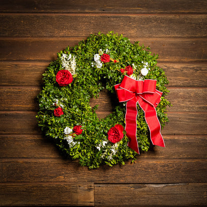 Fresh boxwood with faux red roses, faux white roses, and other faux white flowers with a red and pink-back bow