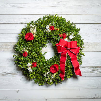 Fresh boxwood with faux red roses, faux white roses, and other faux white flowers with a red and pink-back bow