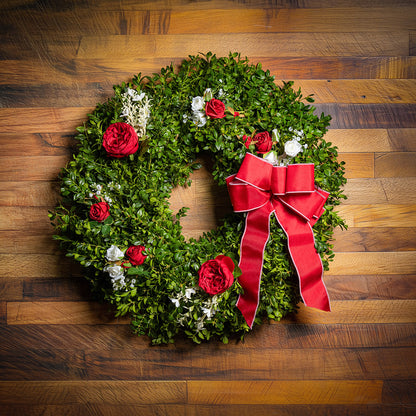 Fresh boxwood with faux red roses, faux white roses, and other faux white flowers with a red and pink-back bow