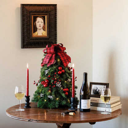 Assembled tree of noble fir,red ornaments, silver berries, red berry branch and a red and black tartan bow