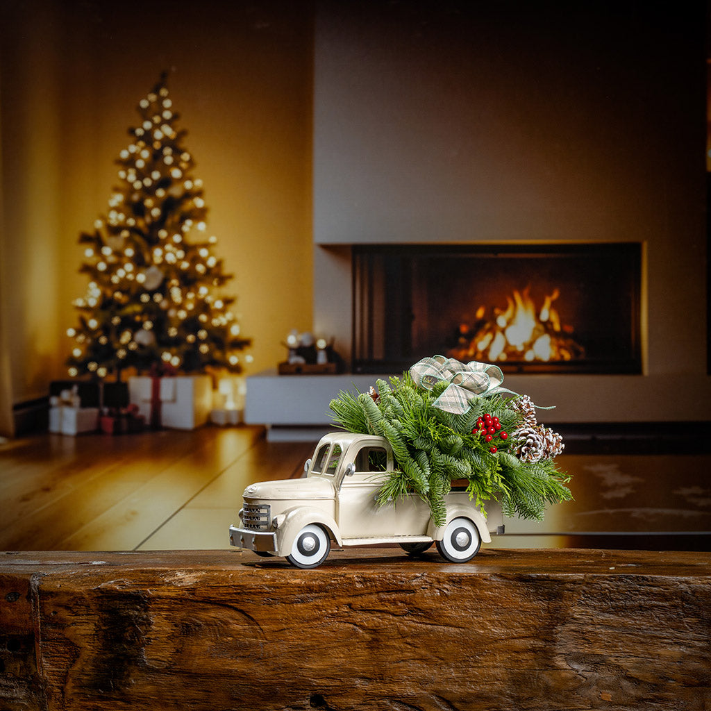 noble fir, cedar, and pine with faux red berries, frosted pinecones, and a sage plaid bow in a cream metal truck container