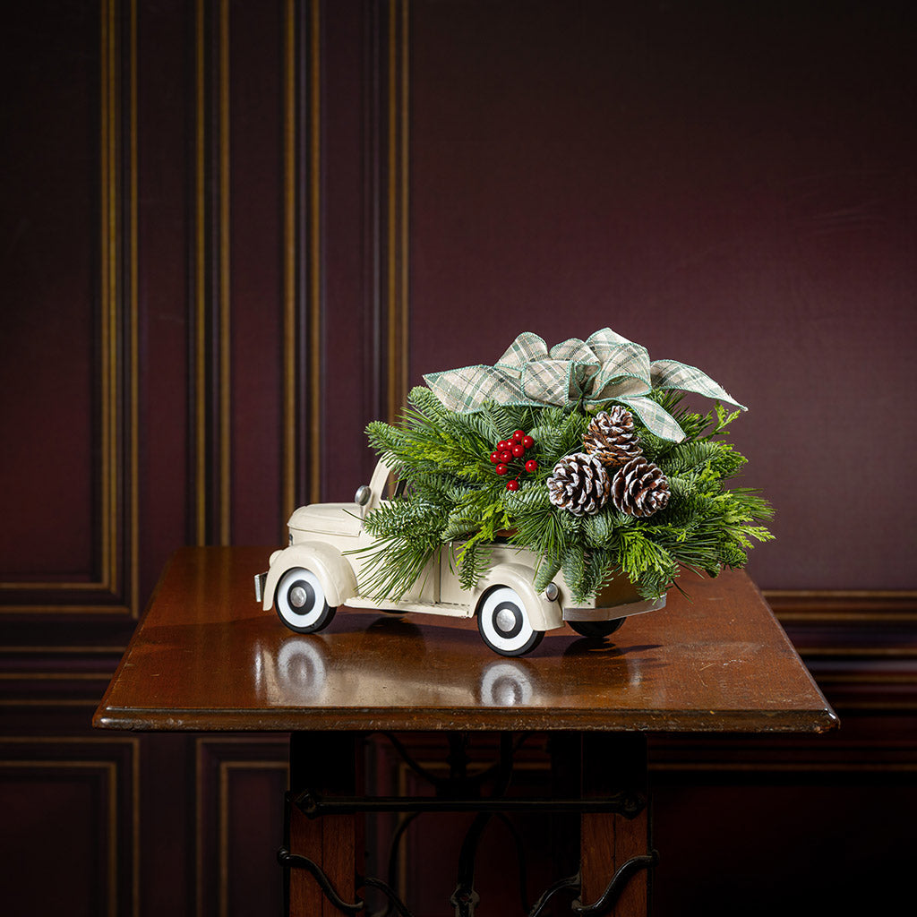 noble fir, cedar, and pine with faux red berries, frosted pinecones, and a sage plaid bow in a cream metal truck container