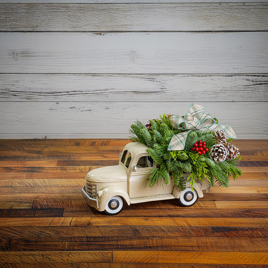 noble fir, cedar, and pine with faux red berries, frosted pinecones, and a sage plaid bow in a cream metal truck container