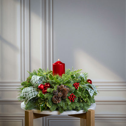 noble fir, cedar, pine, and variegated holly with red ball ornaments, faux red berries, natural pinecones, green-and-white plaid bow tucks, and a red metallic pillar candle