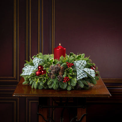 noble fir, cedar, pine, and variegated holly with red ball ornaments, faux red berries, natural pinecones, green-and-white plaid bow tucks, and a red metallic pillar candle