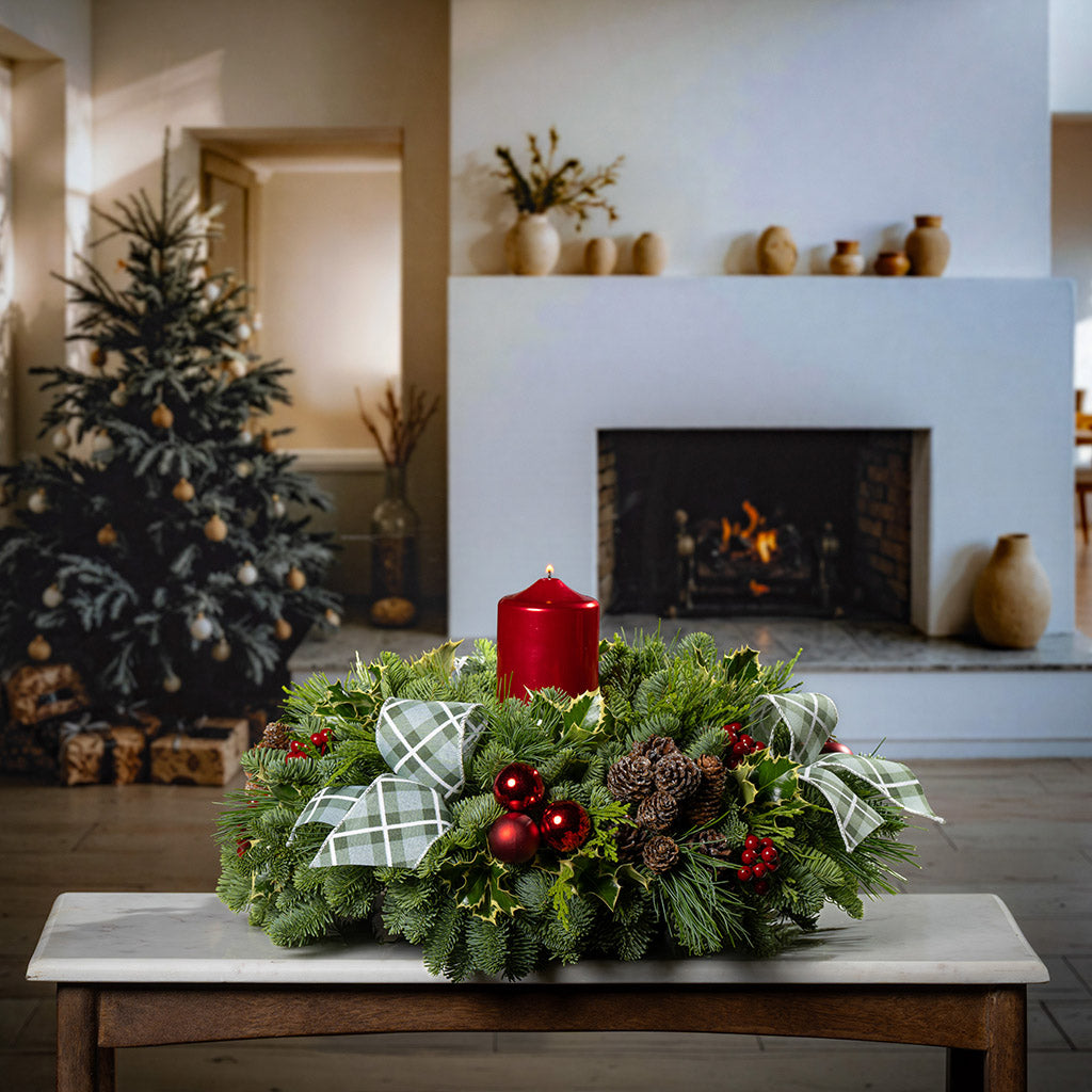 noble fir, cedar, pine, and variegated holly with red ball ornaments, faux red berries, natural pinecones, green-and-white plaid bow tucks, and a red metallic pillar candle