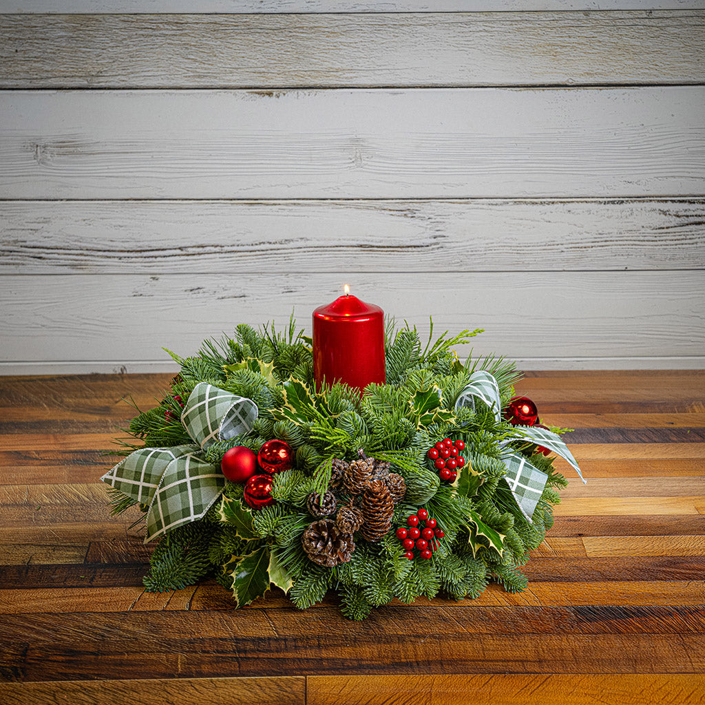 noble fir, cedar, pine, and variegated holly with red ball ornaments, faux red berries, natural pinecones, green-and-white plaid bow tucks, and a red metallic pillar candle