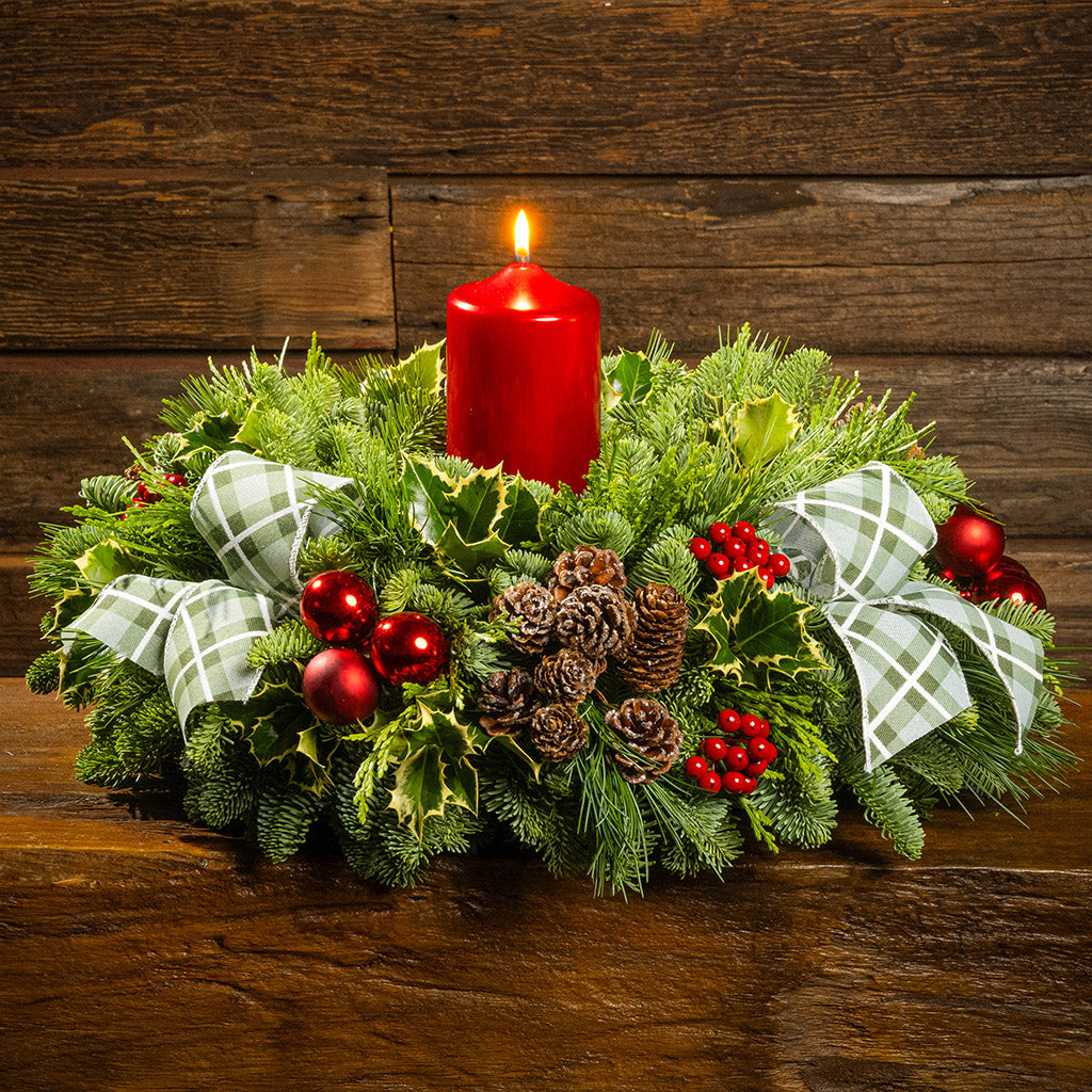 noble fir, cedar, pine, and variegated holly with red ball ornaments, faux red berries, natural pinecones, green-and-white plaid bow tucks, and a red metallic pillar candle